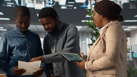 Professional team analyzing archived data on a financial file during meeting, collaborating on...