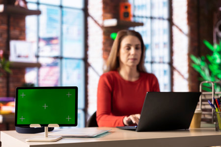 Freelancer uses laptop for creative projects and tasks next to isolated display, creating designs while connected to the freelance platform. Woman focusing on research and sketching.の写真素材