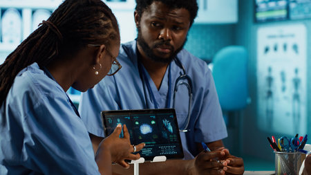 Healthcare professionals discussing patient health records during a meeting, utilizing modern diagnostic tools and technology in a well equipped doctor office. Assistants work with medic. Camera A.の写真素材