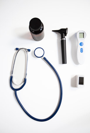 Neat arrangement of a stethoscope, otoscope, oximetry and bottle of pills on white background. The image captures the importance of quality medical instruments for safe patient care.の写真素材