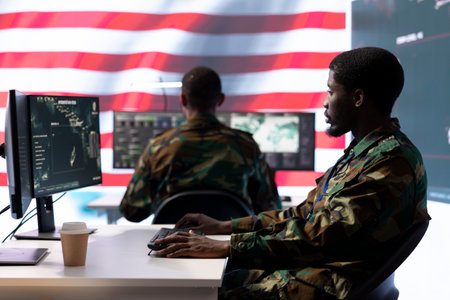 Intelligence officers in american military uniforms work on computers in a command post, managing...