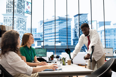 Team of HR workers implementing diversity and inclusivity recruitment strategy for company, hiring man walking with crutches. Coworkers reaching agreement with african american person using canesの写真素材