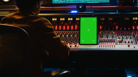 African american audio technician mixing and editing tracks with greenscreen on tablet, working in professional post production studio. Producer creating new tunes for his album. Camera A.の写真素材