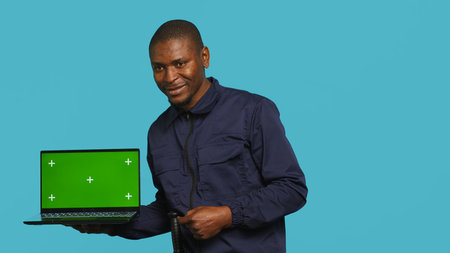 Radiant security guard working protection job presenting mockup laptop. Portrait of joyous bodyguard...