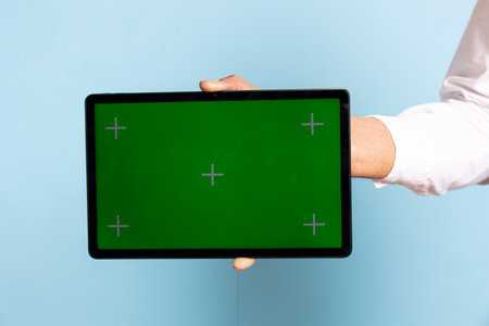 Skilled bellhop holding a tablet with isolated chroma key at the hotel reception, working in...
