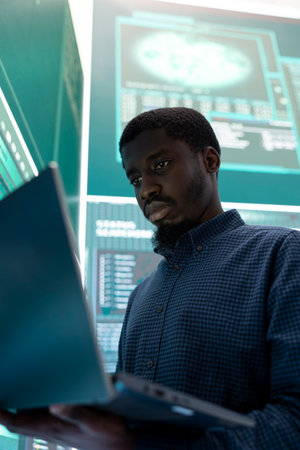 Cyber investigation specialist working in a governmental hacking room, using a laptop and big screen...