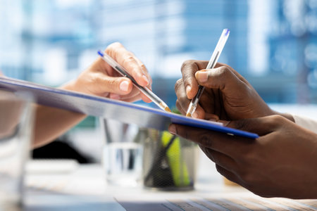 Job interview candidate interested in career advancement, talking with team of HR experts, signing paperwork files. Close up of man writing signature on contract after being hired by recruiterの写真素材