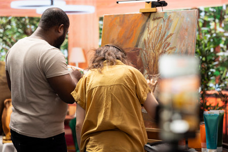 Diverse team of painters recording a vlog to teach people new painting techniques with watercolor,...
