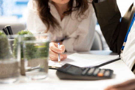 Team of investors calculating new financial projection plan to increase budget for the company expansion, finding ways to obtain more funds. Staff uses calculator for accounting analysis. Close up.の写真素材