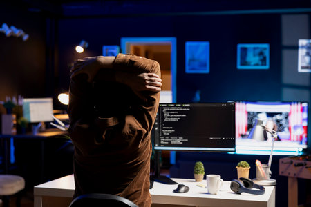 Programmer doing software quality assurance, stretching arms behind back after reading source code, feeling fatigued. IT expert taking break from work to relax muscles after inspecting codingの写真素材