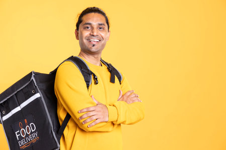Portrait of jolly composed man with positive mood smiling, looking pleased, isolated over studio background. Upbeat person grinning, crossing arms, feeling satisfiedの写真素材
