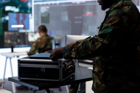 Military staff in a high tech command post gathers intelligence for crucial defense operation, working with satellite radar systems on computers. Supporting troops in field missions.の写真素材