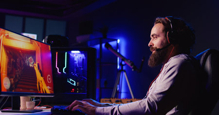 Smiling man reaching final mission in coop FPS videogame, battling flying robots with his online friends. Gamer chats with internet teammates while playing first person shooter game, fighting bossの写真素材