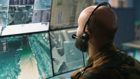 Army specialist working in war room operating surveillance tech, evaluating target data. Close up on dispatcher doing job in HQ base of operations, engaging enemy forces, camera Aの写真素材