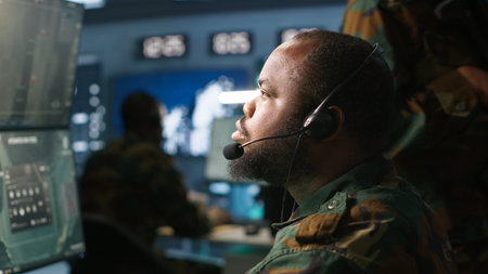 Army telecommunication systems operator using radio and satellite gear, providing combat support. Military dispatcher managing communications networks, looking at screens, camera Aの写真素材