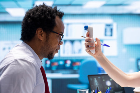 Specialist uses a digital thermometer to check for fever and other flu symptoms, professional tools...