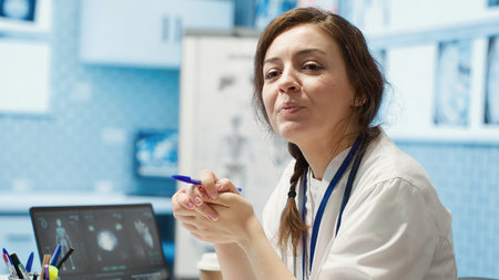Physician meets with a patient to discuss medical results in a cabinet, using advanced diagnostic equipment to interpret x ray scans, demonstrating a professional healthcare approach. Camera A.の写真素材