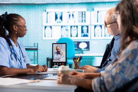 Nurse discussing with patients while being on videocall with specialist, receiving professional diagnosis and advice to recovery. Doctor expert supporting senior clients via internet conference.の写真素材