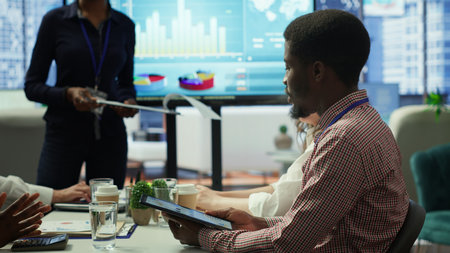 Diverse work team collaborating on project management tasks, utilizing smart technology and detailed analytics to optimize resource allocation and ensure enterprise objectives.の写真素材