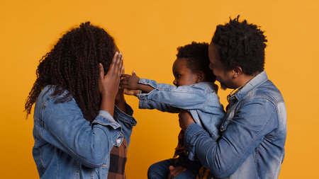 African american happy family fooling around together on camera, smiling parents embracing their small baby boy. Cheerful young mom and dad showing affection to their toddler in studio. Camera A.の写真素材