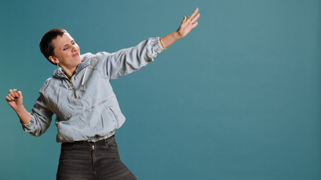 Groovy bold funky woman dancing and fooling around in the studio, acting funny with silly dance moves. Happy confident girl with an urban street style being crazy and edgy.の写真素材
