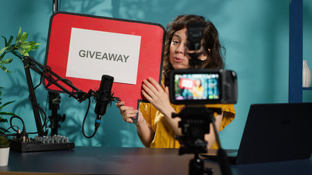 Joyous influencer pointing to empty copy space sign advertising giveaway for fans. Woman offering...