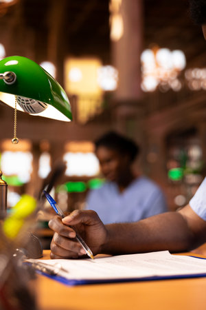 Young person takes notes and does his research for upcoming exams, studying healthcare methods for...