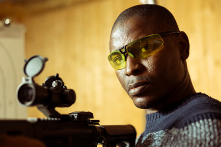 Portrait of man in shooting gallery training, learning proper semiautomatic weapons handling. Person...