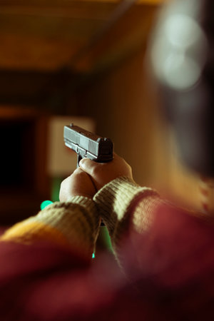 Firing range customer doing shooting activity with pistol during leisure time. Close up of person in shooting gallery learning how to use firearm, pointing it to targets to hit bullseyeの写真素材