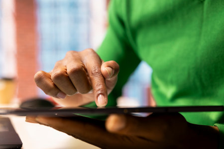 Remote employee at home office desk editing documents on tablet, updating reports and files. Close up of teleworker managing digital documents on device, typing on touchscreen displayの写真素材
