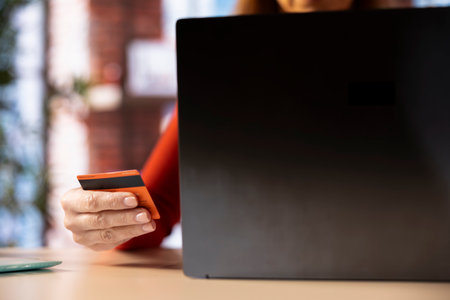 Casual woman at home entering her card digits to renew an account subscription, managing the services on her laptop. Person transferring money on the internet, updating the credentials.の写真素材