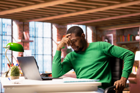 Remote employee at home office desk waiting for laptop operating system to open, feeling bored....
