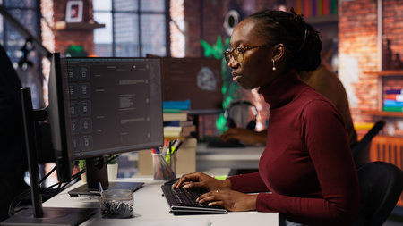 IT startup worker using large language model application to get help with coding tasks. Woman interacting with AI LLM chatbot on PC in software development workplace, camera Bの写真素材
