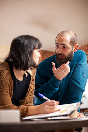 Closeup on businessman and woman with clipboard discussing about startup company revenues. Young...