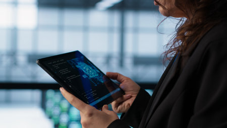 Engineer in data center with tablet integrating AI driven automation tools. Worker ensuring continuous uptime of server room using artificial intelligence, managing data flows, camera Aの写真素材