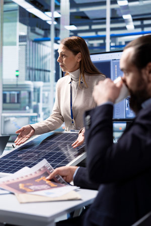 Photovoltaics factory industrial production managers looking over schematics, planning work on facility floor. Solar panels manufacturing plant engineers design assembly lines, looking over blueprintsの写真素材