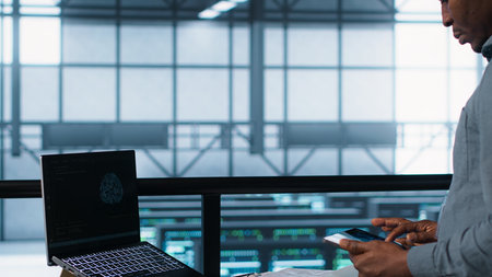Technician in data center with laptop and tablet integrating AI driven automation tools. Server room...