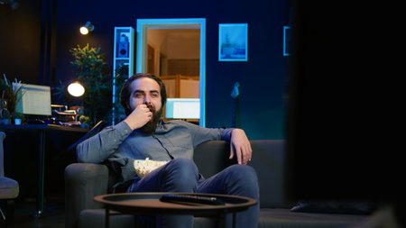 Joyous homeowner using TV to watch comedy films on streaming services, laughing at funny jokes....