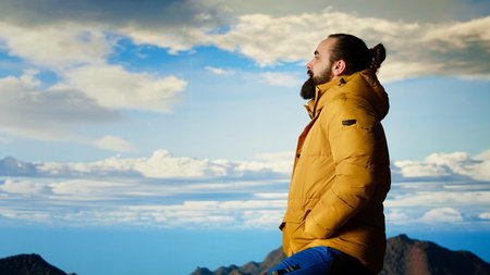 Hiker takes a moment to admire the panoramic view of mountains, looking into the distance and sightseeing. Fresh air, scenic background and peaceful surroundings for an explorer. Camera B.の写真素材