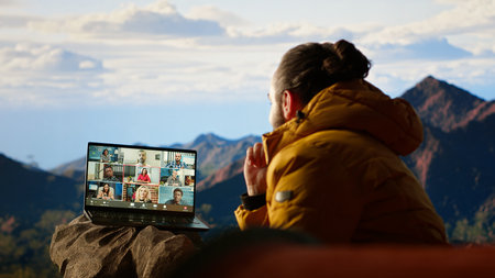 Entrepreneur uses high speed internet connection on mountain top, enjoying the video call with a scenic landscape. Young hiker having an internet dependency and being workaholic.の写真素材