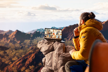 Business employee uses high speed internet connection on mountain top, enjoying the video call with a scenic landscape. Male hiker with an internet dependency.の写真素材