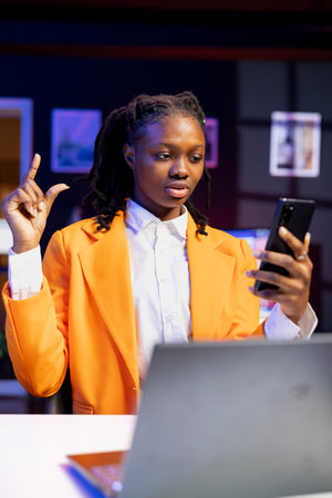 Woman receiving phone call, talking with best friend during videoconference using smartphone in...