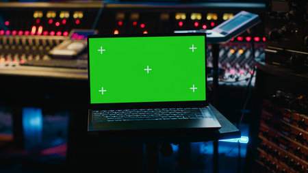 Music producer recording tracks next to laptop showing mockup isolated display, working with mixing console and mastering techniques in control room. Audio engineer producing new tunes. Camera A.の写真素材