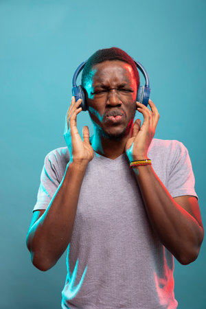 Male influencer with wireless headset, enjoying beautiful sounds and feeling the rhythm. Black man...