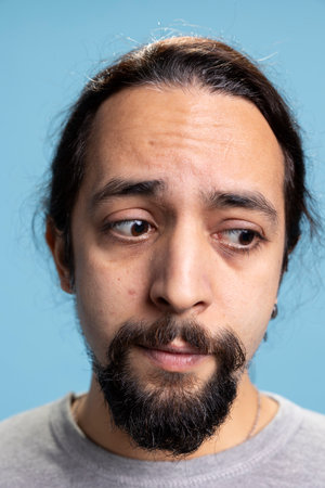 Confused distraught young man feeling troubled and anxious in studio, feeling overwhelmed in...