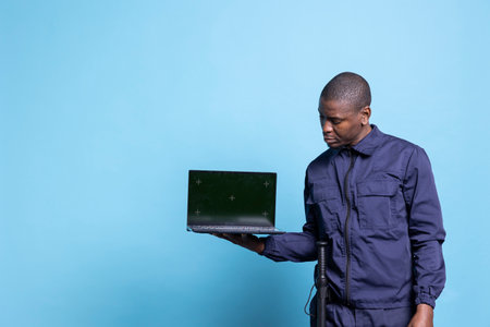 Male security agent pointing at his laptop screen with mockup, presenting a greenscreen while he...