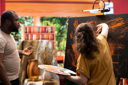 Talented artist and her apprentice engage in finger painting hobby in art and craft workshop, using a modern painting technique to create an abstract masterpiece. Vibrant colors on the canvas.の写真素材