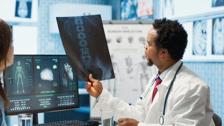Medic expert showing the x ray imaging test results to patient at check up, discussing about treatment. Doctor pointing at radiography scans for interpretation, diagnostic report. Camera A.の写真素材