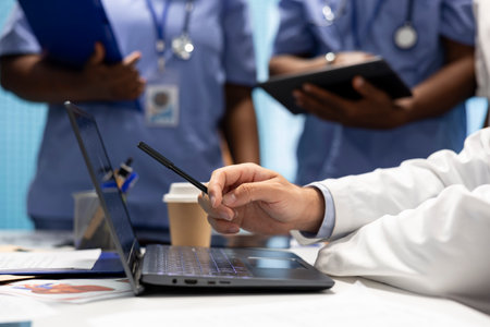 Doctor expert examining radiography scan results and healthcare records on laptop, discussing with team about potential treatment. Medics collaborating on disease prevention. Close up.の写真素材