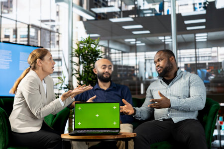 Isolated screen notebook next to multiethnic team working in office, coordinating company administrative operation. Diverse coworkers reviewing business data metrics on chroma key laptopの写真素材